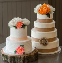 Two white wedding cakes topped with orange and white flowers