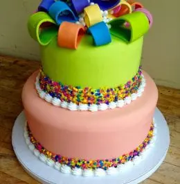 A multicolored wedding cake topped with edible ribbons