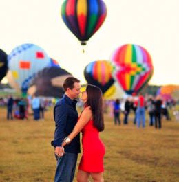 Couple standing together in front of hot air balloons